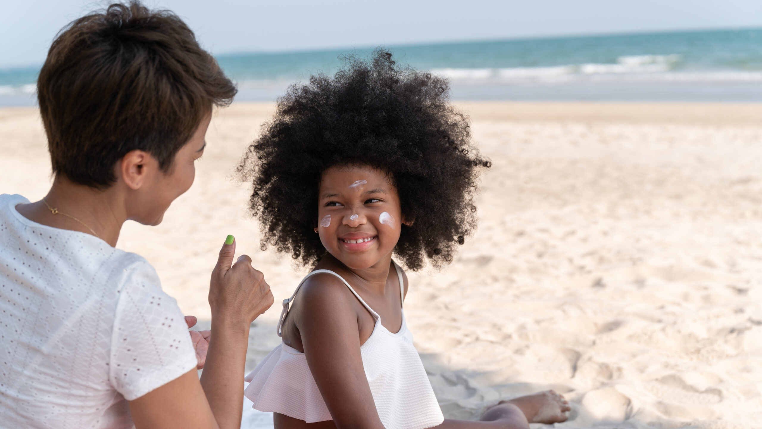 Mom,Applying,Sunscreen,On,The,Back,Of,A,Daughter,On